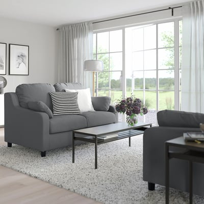 Modern living room with grey VINLIDEN sofa, glass coffee table, side table, and large window with curtains.