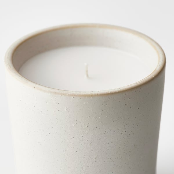Cylindrical candle in textured jar, unlit, speckled.