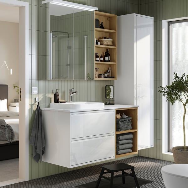 White vanity with marble, mirror cabinet, stool, & towels. Modern decor.