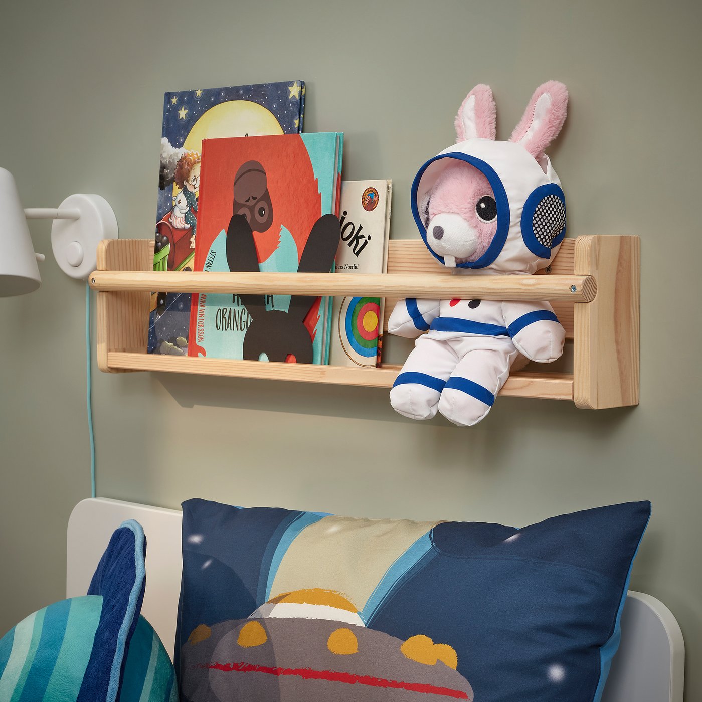 Wooden shelf with kids books & astronaut toy above bed