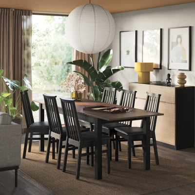 Modern dining room with extendable ÅLHULT table, wooden chairs, and large round lantern, surrounded by plants and decor.