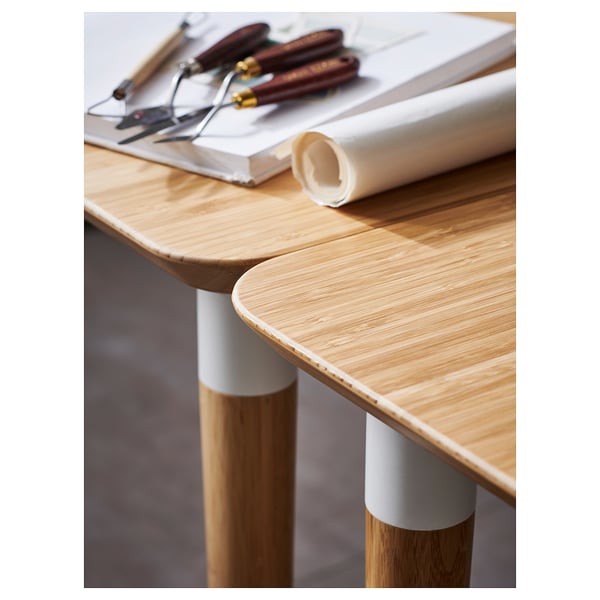 Modern wooden desk with light bamboo top, legs, and white connectors; designed for easy assembly. Tools on top.