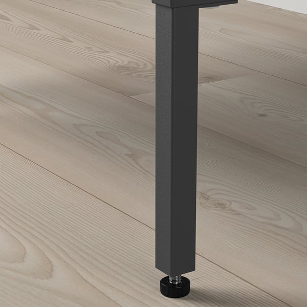 Close-up of sturdy black metal table leg with adjustable foot, supporting wooden tabletop.