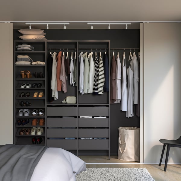Modern walk-in closet with AURDAL grey storage, hanging rails, and drawers. Organised with white and tan clothing. Minimalist bedroom hints seen.