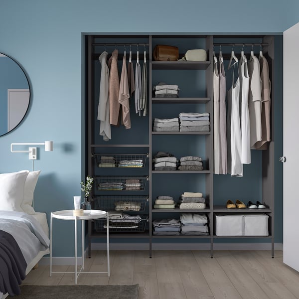Open closet AURDAL, light blue. Flexible storage shelves & hanging space. Shoe rack at base. White side table. Bed with white linens left.