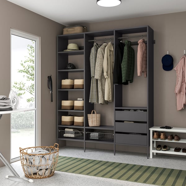 Black shelves and drawers in closet, wicker bins, clothes, white shoe rack, striped rug.