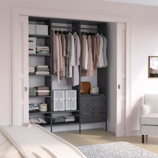 Modern closet with pastel clothes, grey AURDAL shelves, pink walls, and side chair.