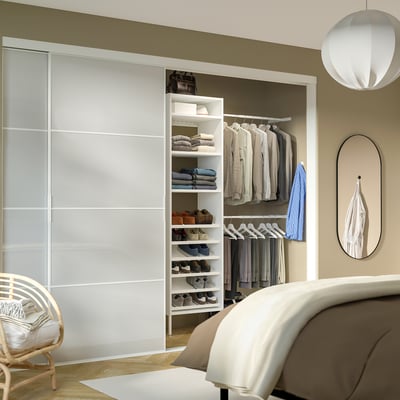 Modern bedroom with AURDAL white closet, neatly organised. Visible bed, mirror, and pendant light, well-lit ambiance.