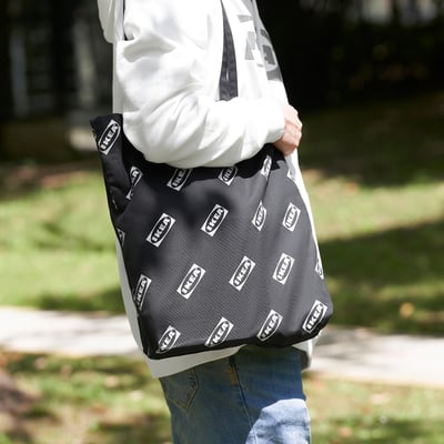 Person carrying black and white ikea shopping bag.
