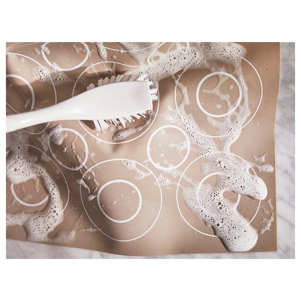 White silicone baking mat with circular patterns, featuring a brush.