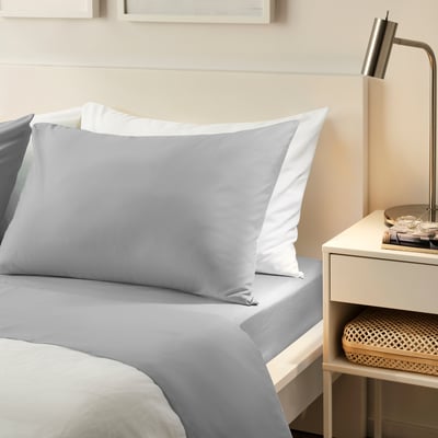 Modern minimalist bedroom featuring BANDPALPMAL grey sheet set on bed, white pillows, sleek bedside table with lamp, and woven basket.