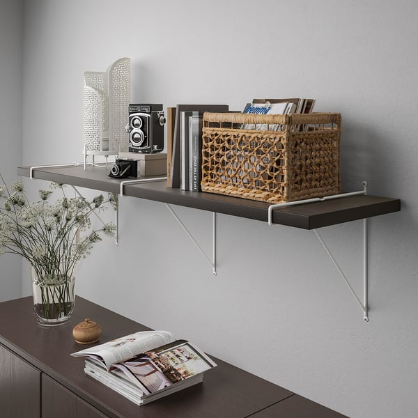 Wall-mounted shelf with books and basket, displaying various items. Brackets visible, supporting the shelf.