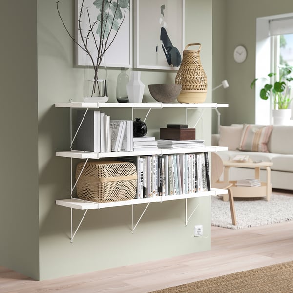 Modern living room with BERGSHULT wall shelf holding decorative items, green wall, and wooden floor.