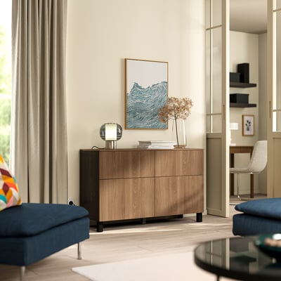 Modern living room with BESTÅ sideboard: light wood, two drawers, lamp, vase, art, blue couch, light hardwood floor.