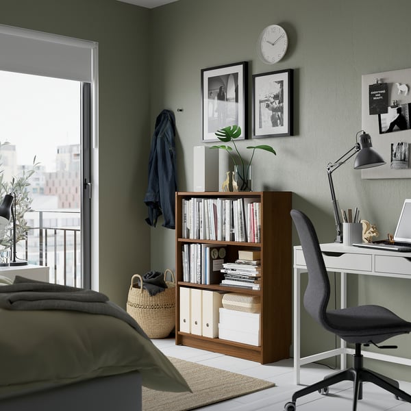 Modern bedroom with BILLY bookcase, desk, chair, plants & city view.