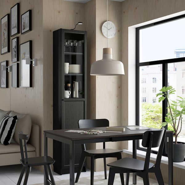 Modern dining with black table, chairs, BILLY cabinet, lamp, clock, couch, plant.