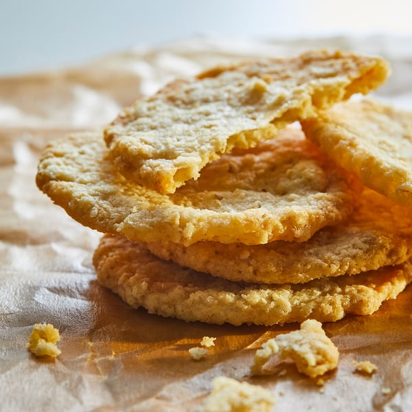 Stack of light golden oat cookies on wooden surface.