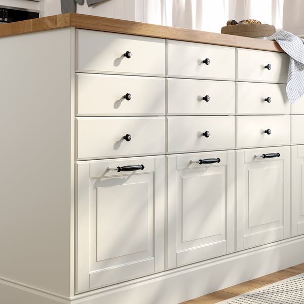 A white BODBYN kitchen cabinet with multiple drawers and doors, featuring bevelled panels and black handles.