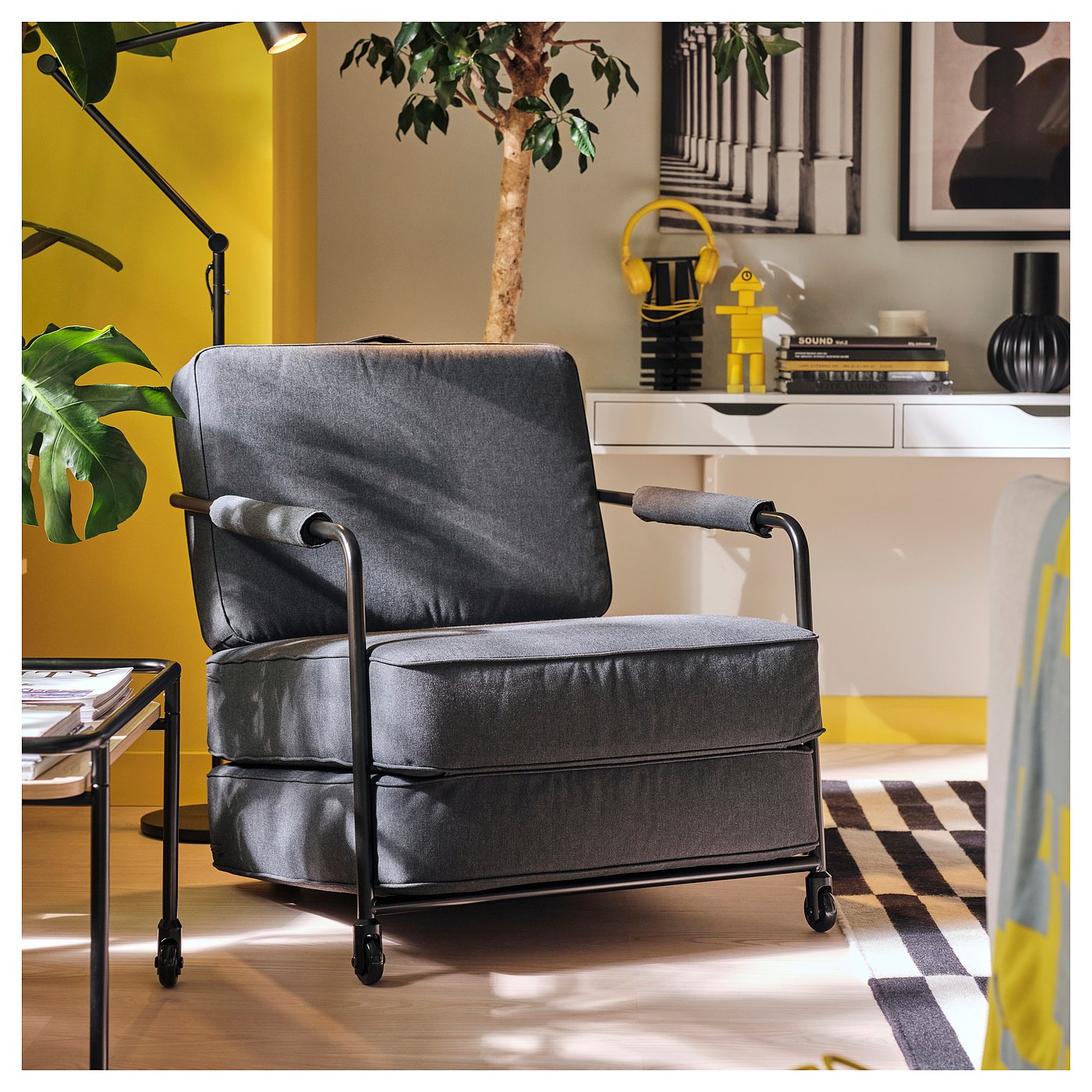 BRÄNNBOLL grey lounge chair, upholstered in polyester, with fold-out seat cushion. Modern, angular design, smaller than surrounding furniture.