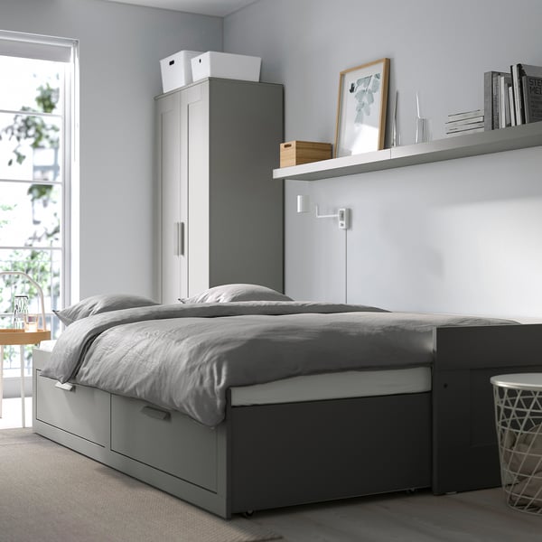 BRIMNES grey day-bed with large storage drawers, compact yet spacious for small rooms, with side table and lamp.