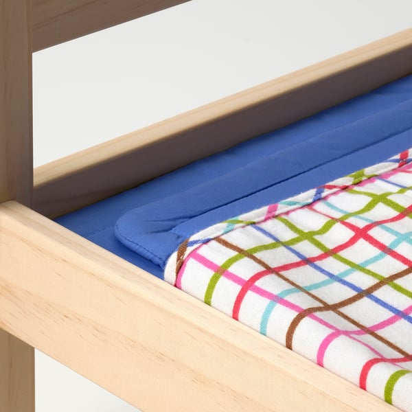 Wooden toy bed with blue mattress, colourful geometric-patterned blanket, and cosy pillow.