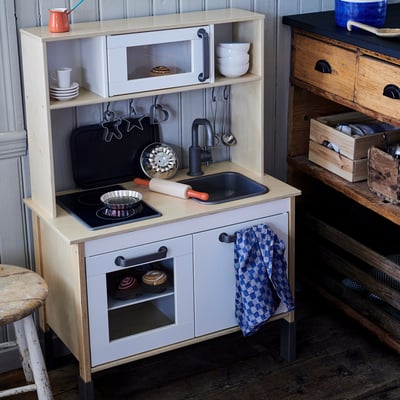 Play kitchen for kids, white with black details, includes sink, stove, oven, and accessories.