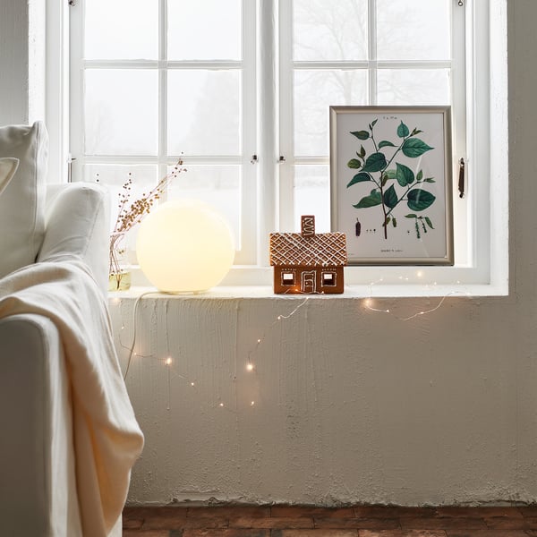 Cosy room with FADO lamp & gingerbread house. Soft light, festive touch.