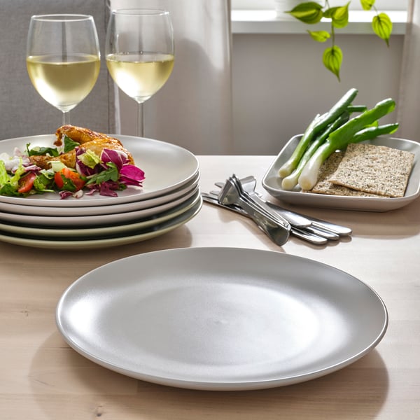 Table set with light grey plates, wine glasses, and a salad.