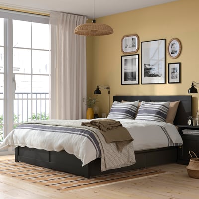 Cosy bedroom with large FÅGELFJÄLLET bed, black oak, under-window balcony, striped pillows, light curtains, and wall art.
