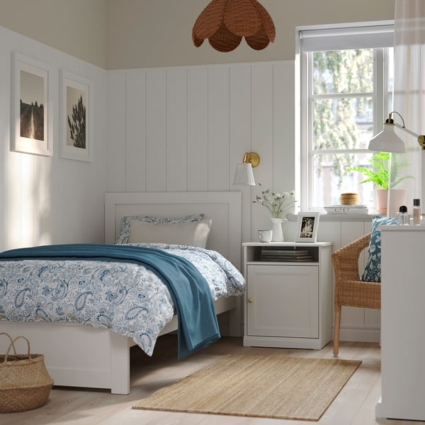 White FÅGELFJÄLLET bedside table with blue bed, top shelf, hidden storage, brass knobs, traditional design.