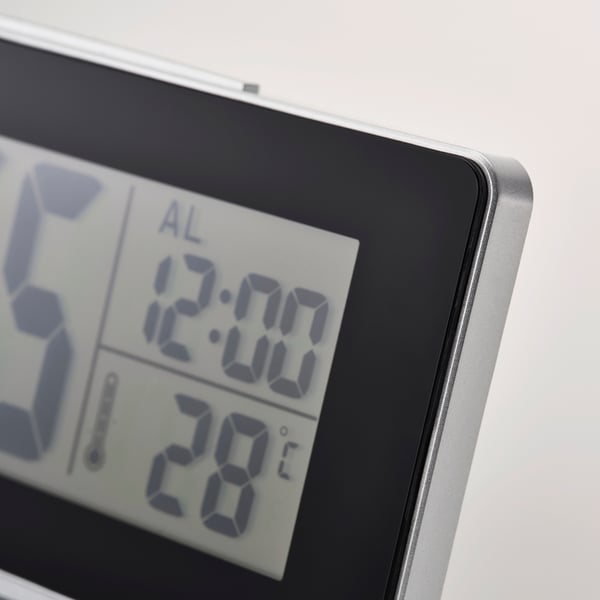 Modern digital clock displays time, alarm, and temperature with clear, large, blue numbers on a black screen, featuring a sleek silver frame.