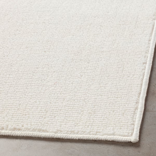 Close-up of a white, textured bath mat, showcasing its soft, quick-drying material and secure latex backing.