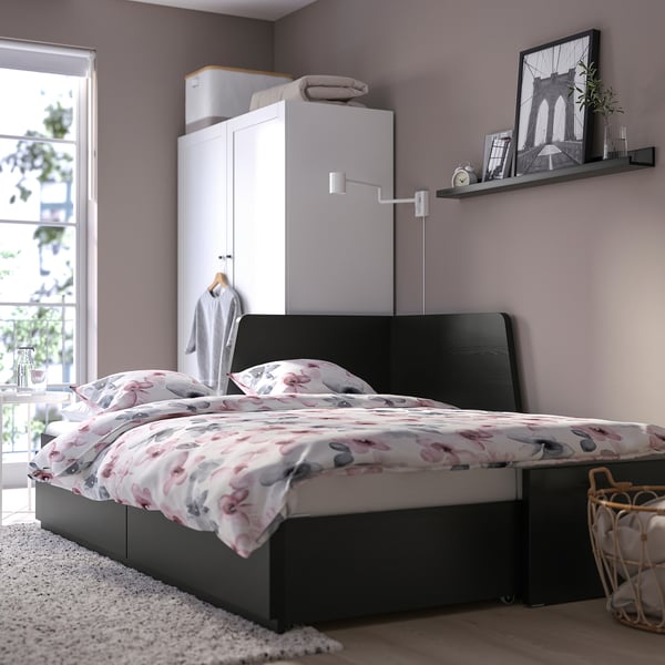 Modern bedroom with grey bed, floral linens, wall shelf, and built-in cabinet. Bed functions as sofa or guest bed.