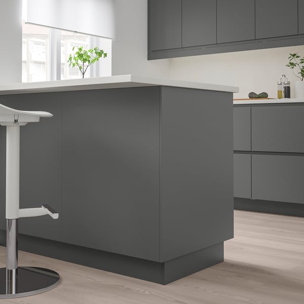 Modern grey FÖRBÄTTRA kitchen island with clean lines and sleek surfaces, featuring white countertop. Its larger than the white stool beside it.