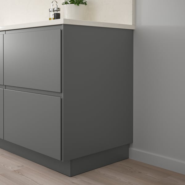FÖRBÄTTRA dark grey unit with sleek modern design, minimalist handles, light wood floor, white countertop, small plant.