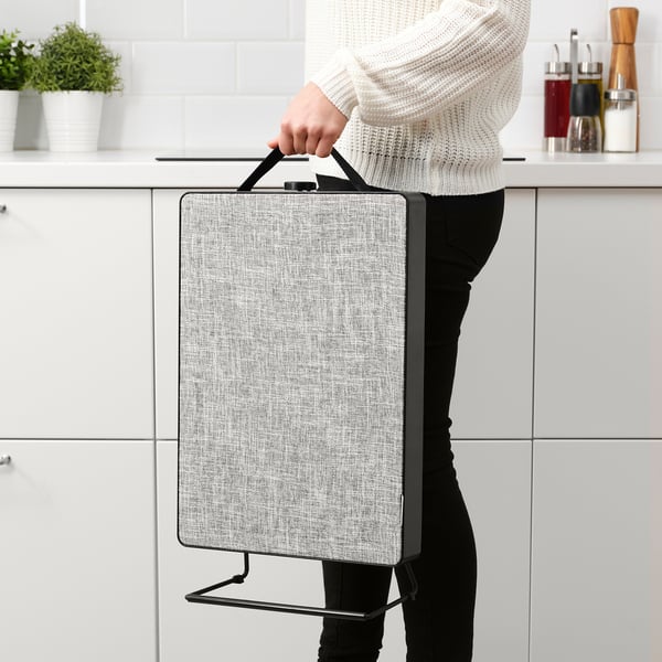 Person holding portable air purifier with handle in kitchen.