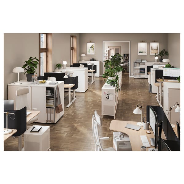 Modern office space with white furniture and plants, featuring desks, chairs, and storage units with sliding doors.