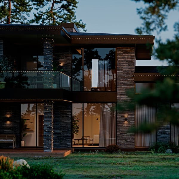 Modern house lit by string lights at night, creating a festive ambiance with dark exterior and greenery.