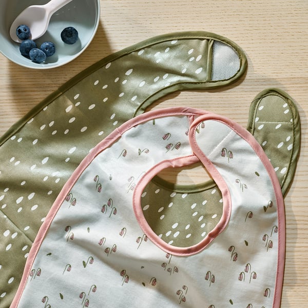 Floral and dotted baby bibs on wooden table, soft inside, waterproof outside.