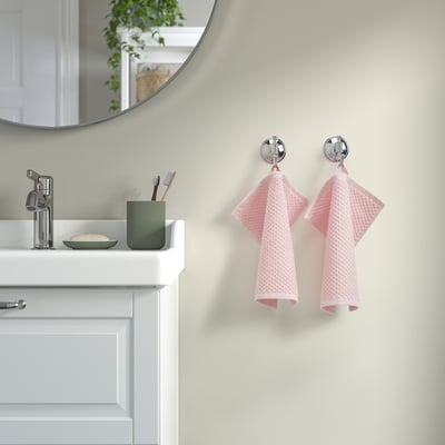 Tidy bathroom with chrome sink, green toothbrush holder, pink GULVIAL towels, and mirror reflecting plants.