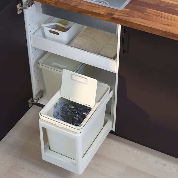 Image shows a white HÅLLBAR waste sorting bin inside a cabinet. Its rectangular, made of recycled plastic, and has a foldable handle.