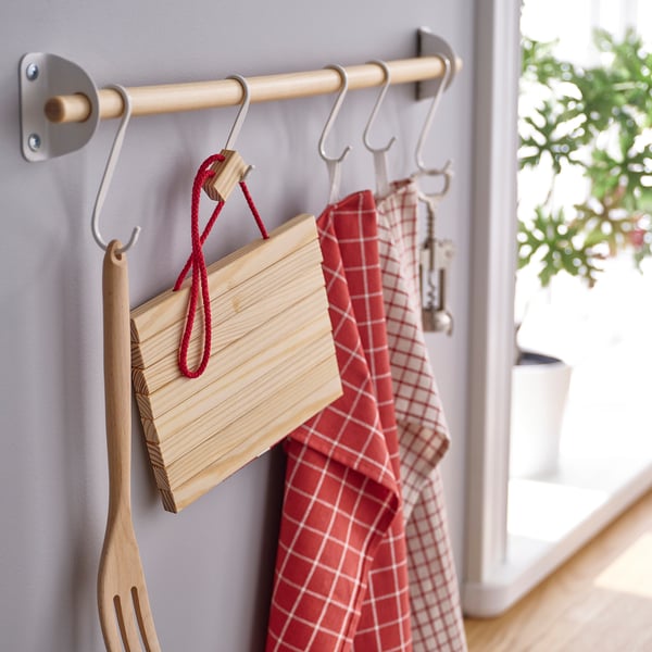Kitchen organiser with hooks holding wooden cutting boards, red chequered towels, and kitchen tools.
