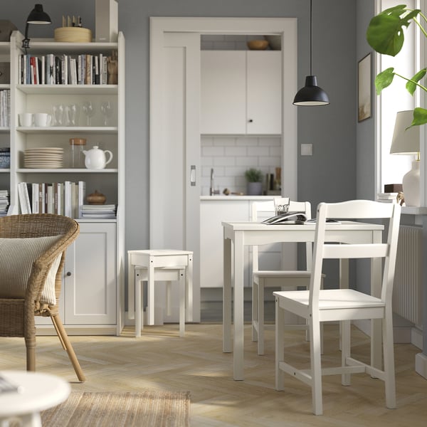Small white wooden dining table and chairs set. Clean, modern design. Part of HAUGA series. Light grey walls and natural wooden floor.