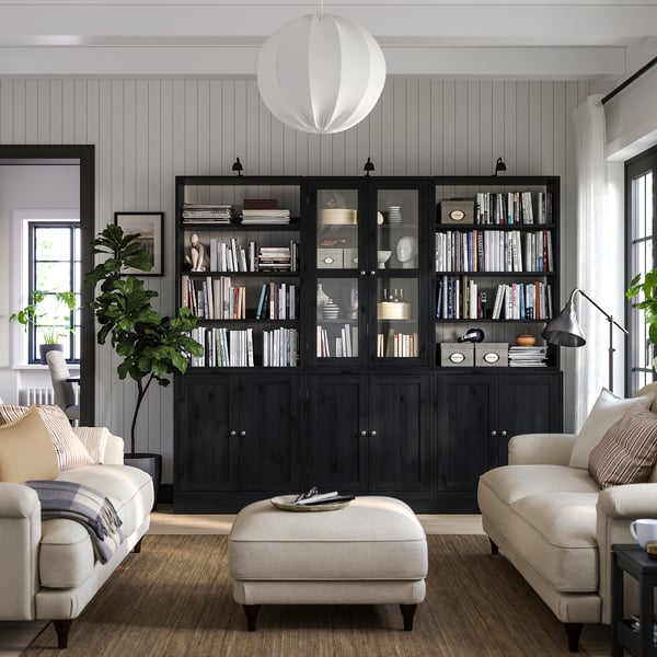Modern living room with black HAVSTA bookshelves, white couches, beige rug, and large window.