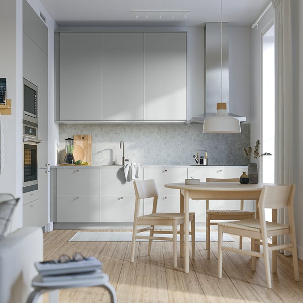Modern kitchen with light grey HAVSTORP cabinets, smooth wood floor, round lightwood table, and minimalist design.