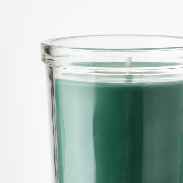Clear glass candle jar with green wax, smooth finish. Holds scented candle with grassy, spicy herb fragrance.