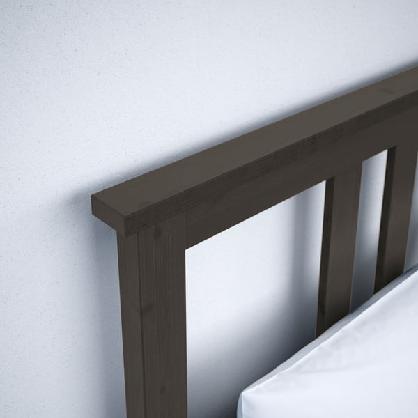 Dark wood HEMNES bed frame corner, sleek headboard, showing high-quality craftsmanship.