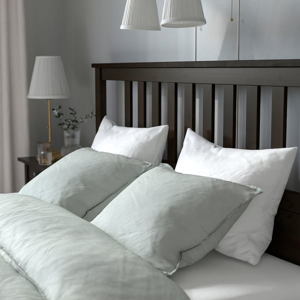 Minimalist bed with wooden headboard, white pillows, and pendant lights. Ideal for relaxation and reading.
