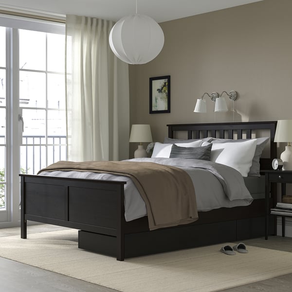 Modern bedroom with dark HEMNES bed, grey linens, pendant lamp, and large windows.