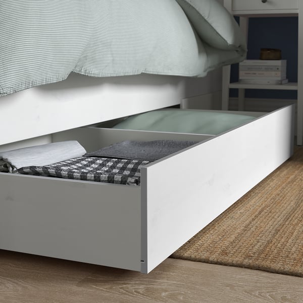 Under-bed drawer with folded blankets and a notebook.